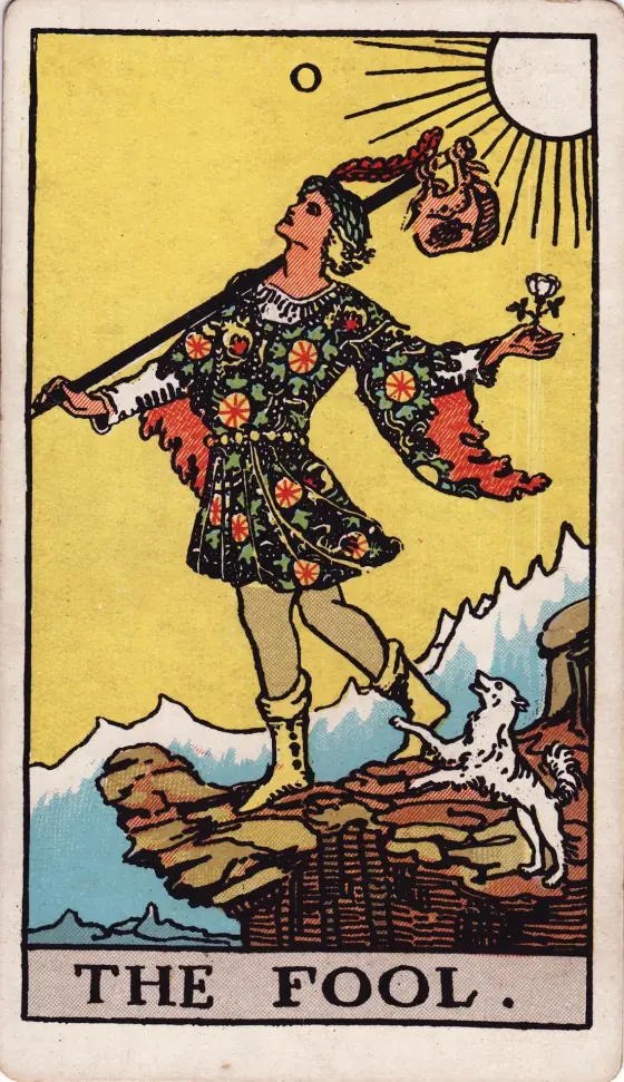Trump 0, the Fool: a young traveller in a bright tunic steps toward a cliff edge, a white rose in one hand and a small dog at his heels.